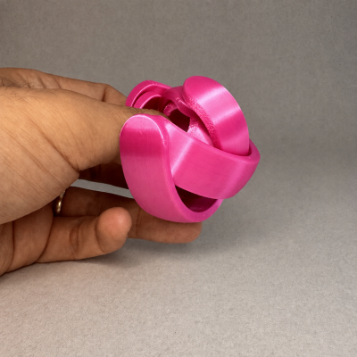 Brinquedo entrelaçado rosa segurado por uma mão contra fundo cinza.