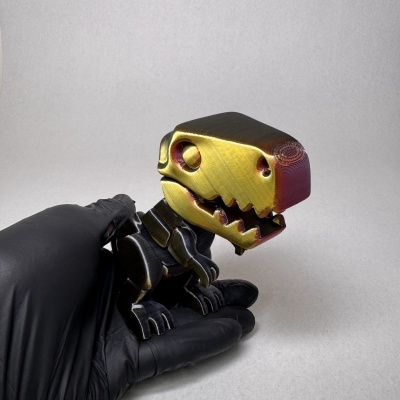 Figura de dinossauro em plástico colorido a preto, amarelo e vermelho numa mão com luva preta