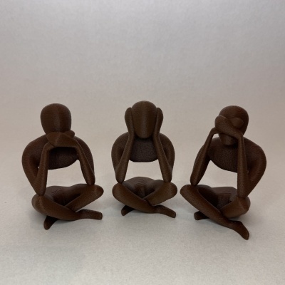 Três estatuetas decorativas marrons de figuras humanas em posições de não ouvir, não ver e não falar num fundo cinza.