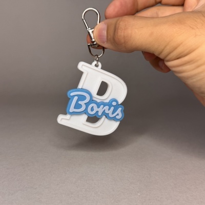 Chaveiro com texto Boris em plástico branco e azul segurado por mão