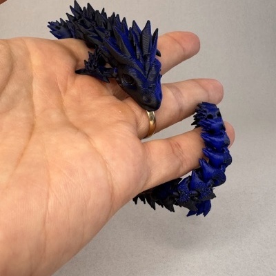 Brinquedo azul escuro em forma de dragão com textura detalhada na mão