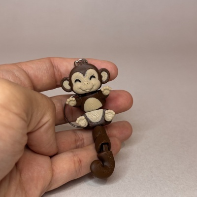 Chaveiro de macaco castanho e bege nas mãos com fundo neutro