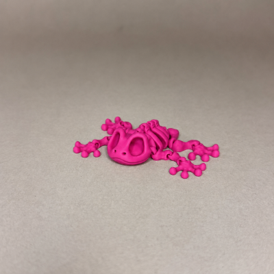 Figura de rã rosa fluorescente em plástico sobre superfície lisa bege