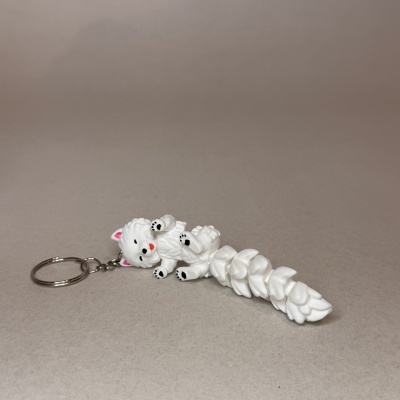 Chaveiro de gato branco articulado em superfície cinzenta