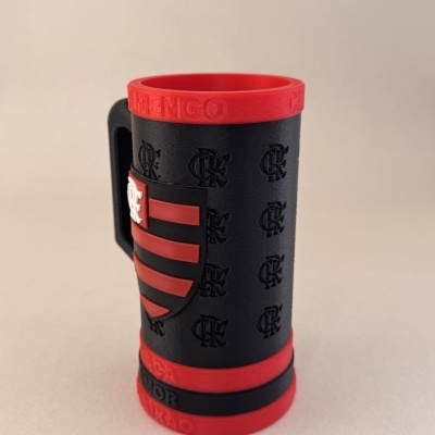 Caneca preta e vermelha com símbolos em relevo e texto na borda