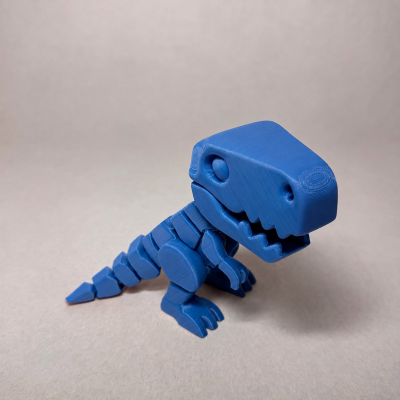 Figurinha de dinossauro azul em plástico sobre fundo cinzento