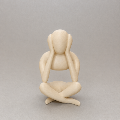 Escultura abstrata creme de figura humana sentada com mãos na cabeça.