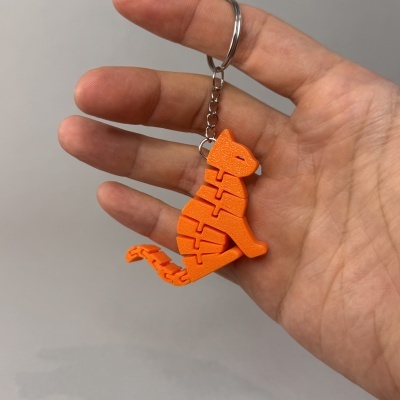 Chaveiro laranja de dinossauro em plástico segmentado na mão