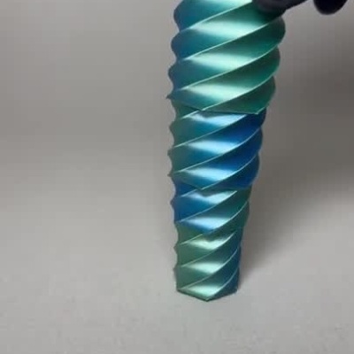 Fresa helicoidal azul e verde sendo manipulada por uma mão com luva preta