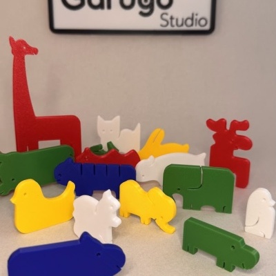 Figuras de animais coloridas em plástico com placa Garugo Studio ao fundo