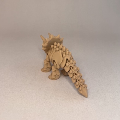 Figura de dinossauro Stegosaurus castanha clara com protuberâncias, sobre superfície cinza.