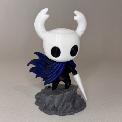 Figura colecionável de personagem com cabeça branca e chifres e capa azul