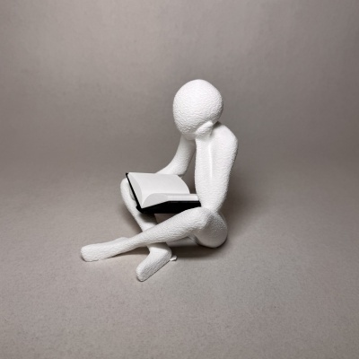 Escultura decorativa branca de figura humana a ler livro