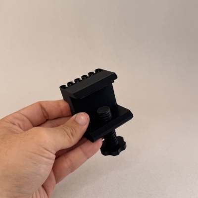 Suporte preto em plástico com parafuso ajustável segurado por mão contra fundo cinza claro
