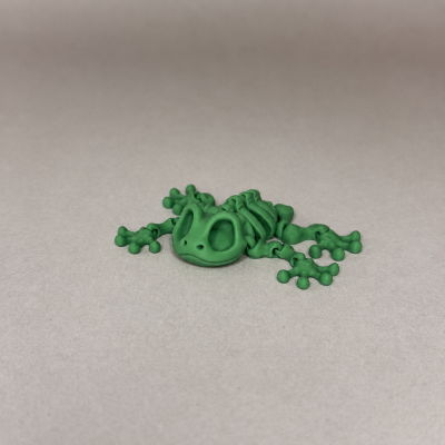 Figura de rã verde de plástico 3D sobre superfície cinza