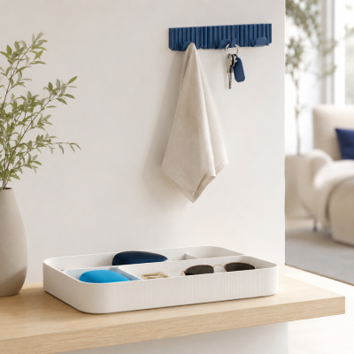 Organizador de mesa branco com divisórias e objetos e cabide azul na parede com pano bege e chaves penduradas
