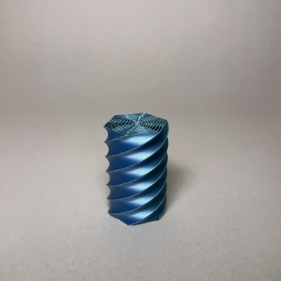 Objeto decorativo azul helicoidal com textura estriada sobre fundo cinzento