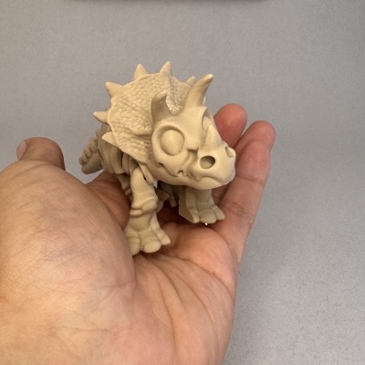 Figura pequena de dinossauro Triceratops bege na mão