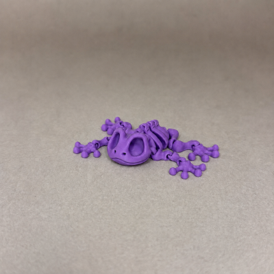 Figura articulada roxa de esqueleto de sapo em fundo bege