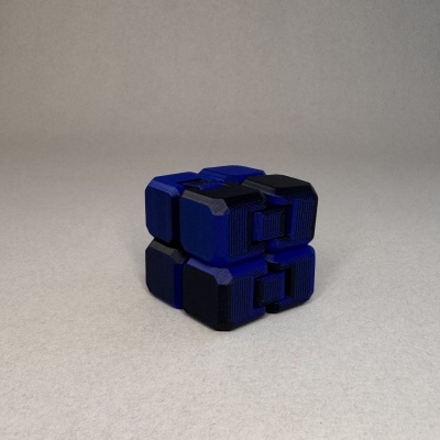 Quebra-cabeça cúbico azul e preto com padrão geométrico sobre fundo cinza