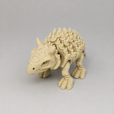 Figura de dinossauro plástico bege com espinhos sobre fundo cinzento claro