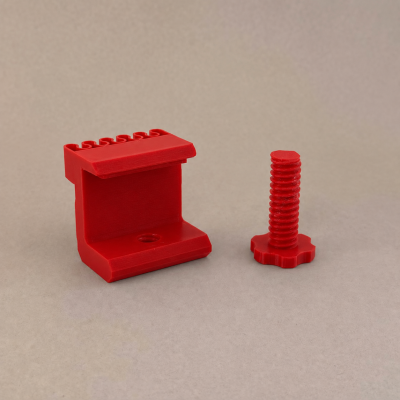 Peças de plástico vermelho em formato de ângulo e parafuso sobre fundo cinzento