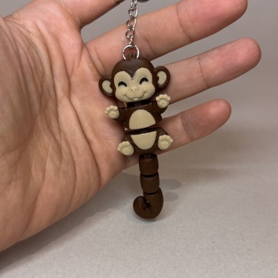 Chaveiro macaco em plástico castanho e bege segurado numa mão