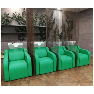 Quatro cadeiras verdes de couro sintético com pias de cabeleireiro no fundo