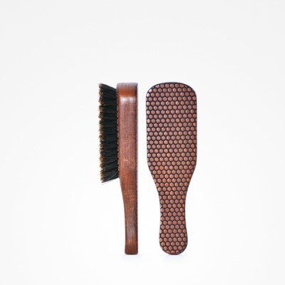 Escova para barba em madeira com cerdas pretas e parte traseira com padrão pontilhado.