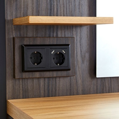 Tomada dupla preta numa parede revestida a madeira castanha escura com prateleira e superfície de madeira clara