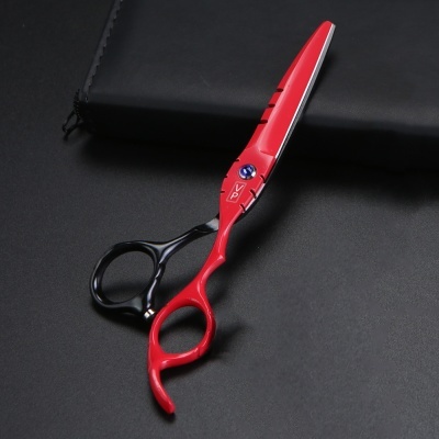 Tesoura profissional vermelha e preta sobre superfície preta com estojo preto.
