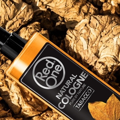 Frasco de colónia Red One sobre folhas secas de tabaco