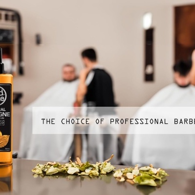 Frasco de colónia natural Red One Tabaco numa barbearia com barbeiros e clientes ao fundo