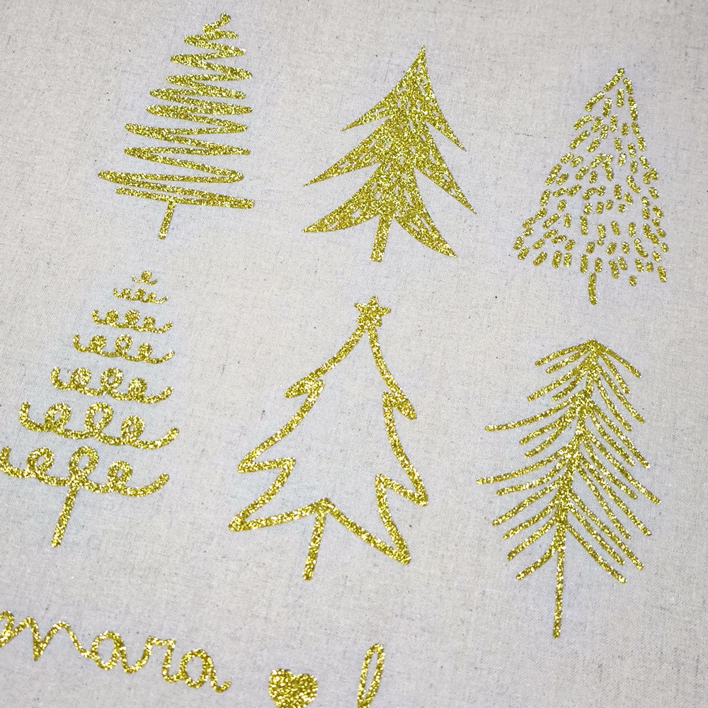 Seis desenhos de árvores de Natal em glitter dourado sobre tecido claro