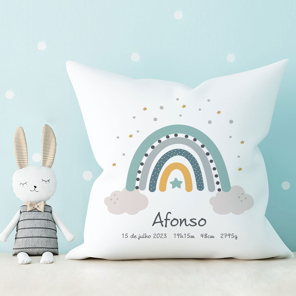 Almofada branca com arco-íris colorido e nome Afonso, ao lado de boneco de coelho de pelúcia
