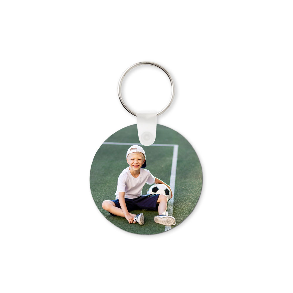 Porta-chaves redondo personalizado com fotografia de criança num campo desportivo.