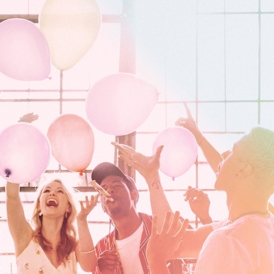 Festa com balões rosa, branco e salmão, pessoas felizes a brincar