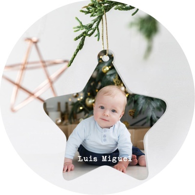 Ornamento em forma de estrela com fotografia de bebé e texto Luis Miguel pendurado em ramo de árvore