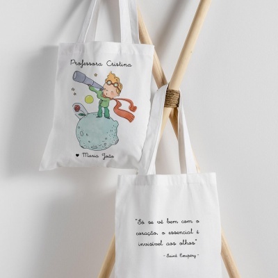 Duas bolsas de pano branco com ilustrações e texto penduradas em estrutura de madeira