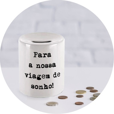 Pote de cerâmica branco com texto para poupar para uma viagem, com moedas ao redor