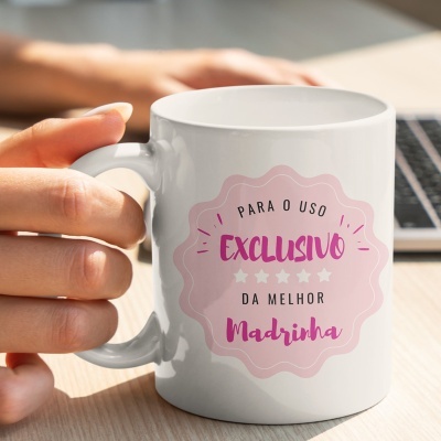 Caneca branca com texto PARA O USO EXCLUSIVO DA MELHOR Madrinha em etiqueta rosa
