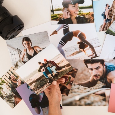 Fotografias impressas de atividades ao ar livre sobre mesa branca com lente de câmera