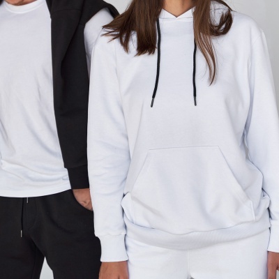 Duas pessoas com roupa casual em branco e preto, hoodie branca com cordões pretos e pocket frontal, e camiseta branca com calças pretas.