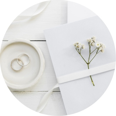 Anéis de casamento em recipiente branco ao lado de envelope branco decorado com flores