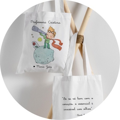 Sacolas de pano brancas com ilustrações e texto em português penduradas em estrutura de madeira