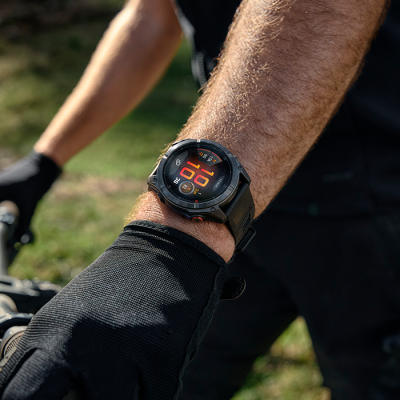 Relógio digital preto com bracelete preta no pulso de uma pessoa com luva preta.