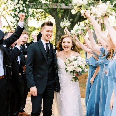 Noivos e convidados em casamento ao ar livre com vestuário formal e buquê de flores