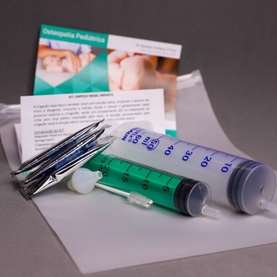 Seringas plásticas com líquido verde e embalagens sobre superfície cinza