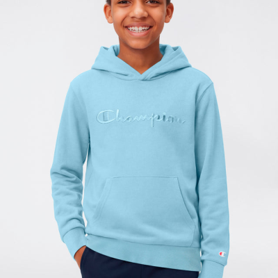 Rapaz a usar camisola azul clara com capuz da marca Champion e calças escuras
