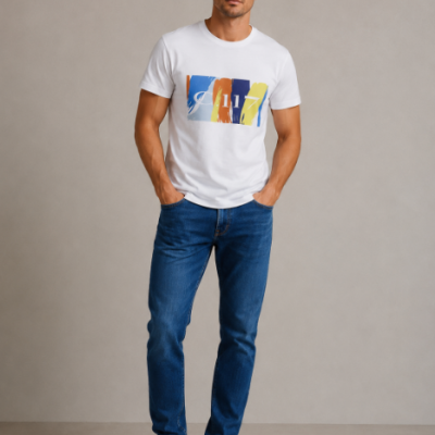 Homem com t-shirt branca estampada, jeans azul escuro e ténis brancos em fundo cinzento